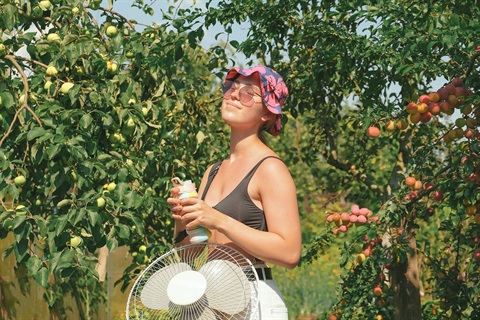 woman with water and fan and sun hat and sun glasses